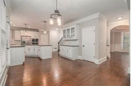 4519 Mossey Dr, Lithonia, GA 30038 - kitchen featuring arched walkways, white cabinetry, dark wood finished floors, a chandelier, and pendant lighting