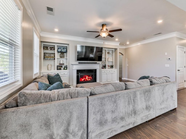 living area with visible vents, arched walkways, dark wood-style floors, and crown molding