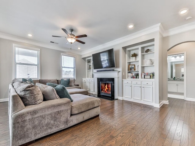 living area featuring a premium fireplace, visible vents, dark wood-type flooring, and ornamental molding