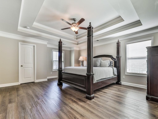 unfurnished bedroom featuring baseboards, a raised ceiling, wood finished floors, and ornamental molding