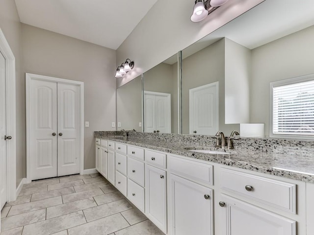 bathroom featuring double vanity, baseboards, and a sink