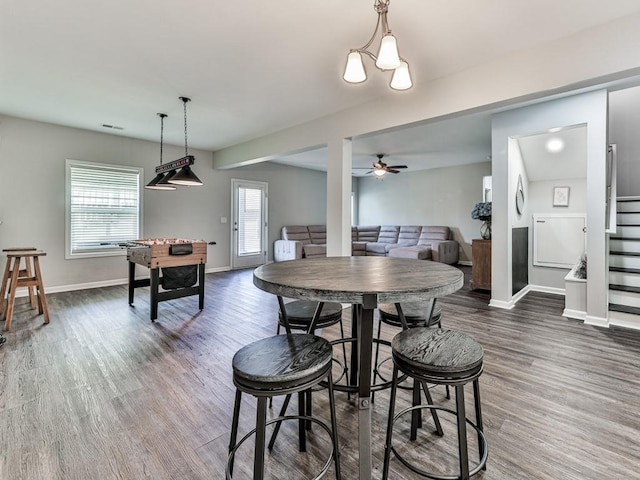 dining area featuring stairway, baseboards, a ceiling fan, and dark wood-style flooring