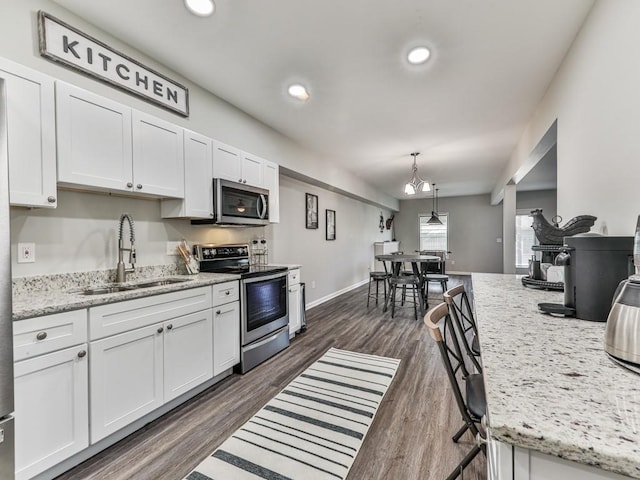 kitchen featuring dark wood-style floors, white cabinets, stainless steel appliances, and a sink