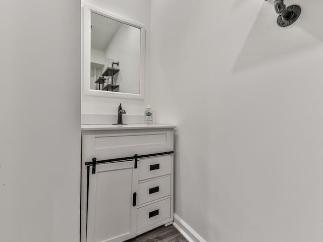 bathroom with vanity, wood finished floors, and baseboards