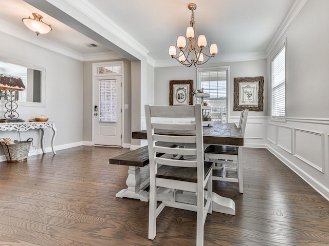 dining room with visible vents, a notable chandelier, ornamental molding, hardwood / wood-style flooring, and a decorative wall