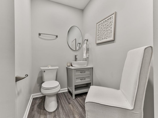 bathroom with vanity, toilet, wood finished floors, and baseboards