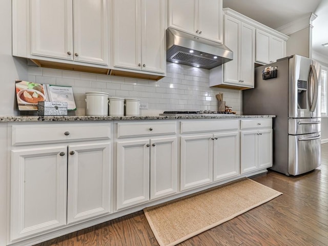 kitchen with tasteful backsplash, under cabinet range hood, appliances with stainless steel finishes, white cabinetry, and dark wood-style flooring