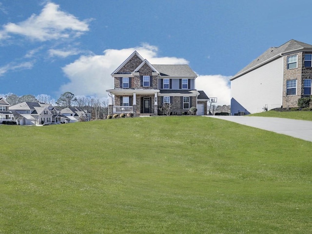 view of front of home featuring a front yard, covered porch, a garage, stone siding, and driveway