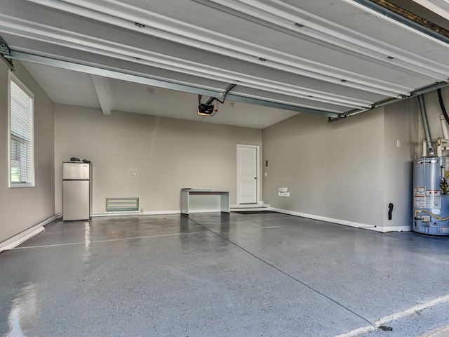 garage featuring baseboards, a garage door opener, water heater, and freestanding refrigerator