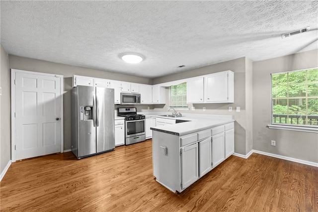 470 Piney Way SW, Atlanta, GA 30331 - kitchen with appliances with stainless steel finishes, a sink, a peninsula, wood finished floors, and white cabinets