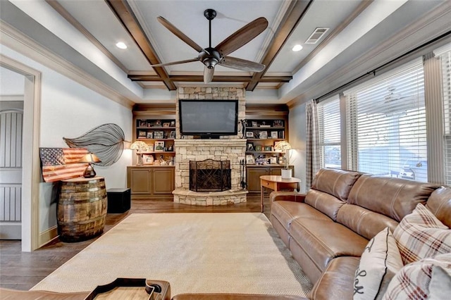 living room featuring a stone fireplace, ceiling fan, wood-type flooring, coffered ceiling, and beamed ceiling