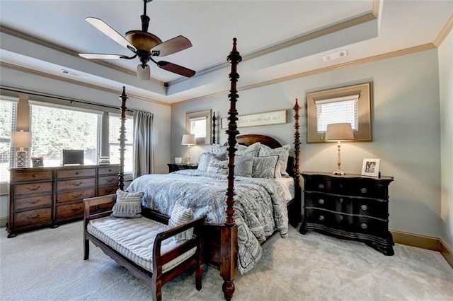 carpeted bedroom with ceiling fan, a tray ceiling, and ornamental molding