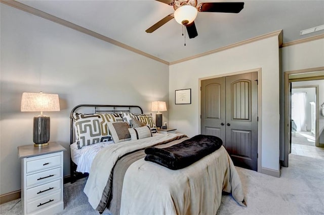 bedroom with light carpet, crown molding, ceiling fan, and a closet