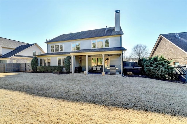 back of house featuring ceiling fan, a patio area, and a hot tub