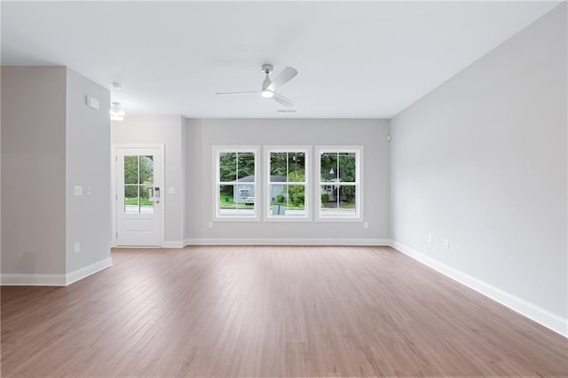 empty room with a ceiling fan, baseboards, and wood finished floors