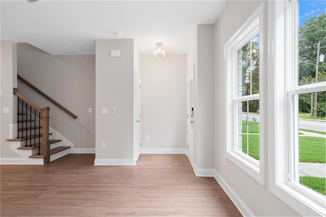 entryway featuring light wood-type flooring, baseboards, and stairs