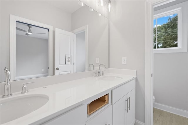 full bath with double vanity, baseboards, and a sink