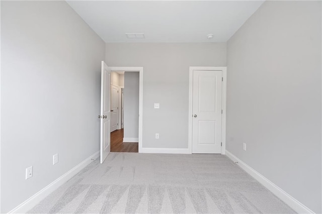 unfurnished bedroom featuring visible vents, baseboards, and light colored carpet