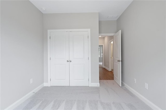 unfurnished bedroom featuring light carpet, a closet, visible vents, and baseboards