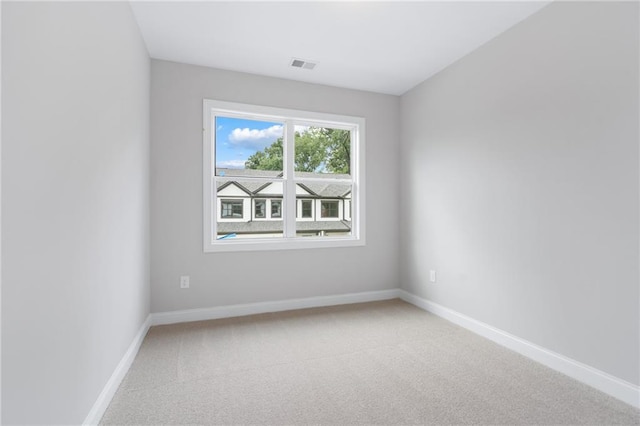 spare room featuring carpet floors, visible vents, and baseboards