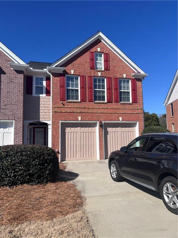 view of front facade with driveway, brick siding, and an attached garage