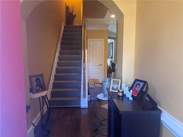 staircase with baseboards, crown molding, arched walkways, and wood finished floors