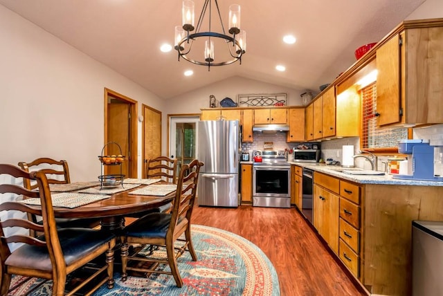 kitchen featuring appliances with stainless steel finishes, pendant lighting, lofted ceiling, sink, and dark hardwood / wood-style flooring