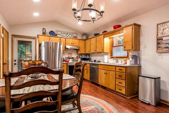 kitchen featuring appliances with stainless steel finishes, pendant lighting, lofted ceiling, sink, and an inviting chandelier