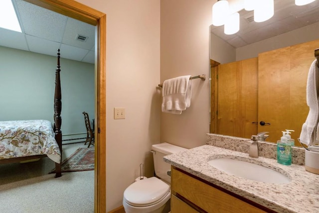 bathroom featuring vanity, a baseboard heating unit, a paneled ceiling, and toilet