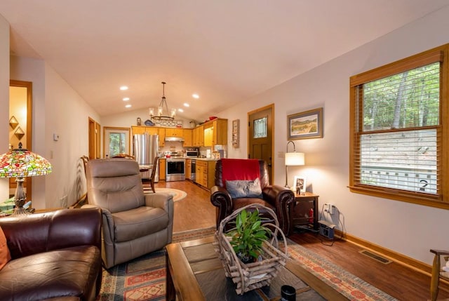 living room featuring lofted ceiling, a chandelier, and light hardwood / wood-style floors