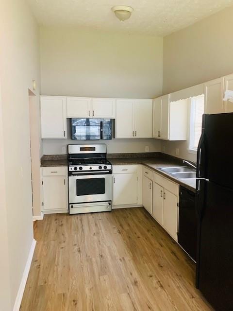 kitchen with high vaulted ceiling, black appliances, sink, and light hardwood / wood-style floors