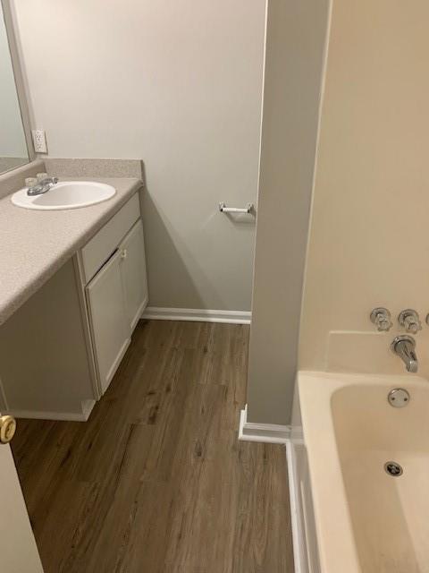 bathroom with a bath, vanity, and wood-type flooring