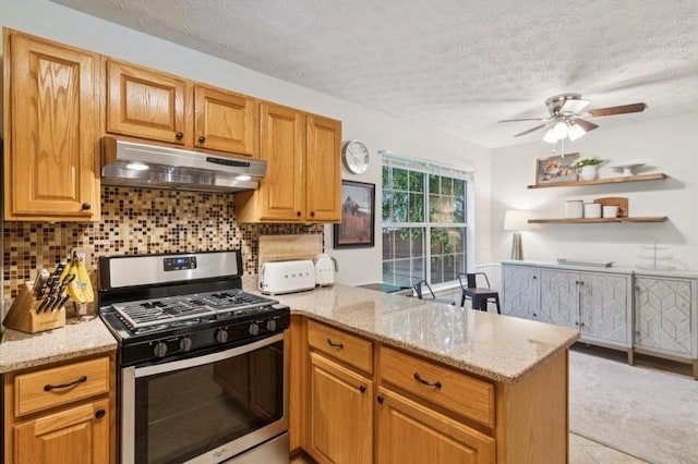 2277 Lazy Days Rd, Dacula, GA 30019 - kitchen with stainless steel gas stove, under cabinet range hood, a peninsula, backsplash, and light stone countertops
