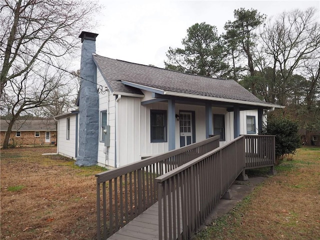 bungalow-style house featuring a chimney, a porch, and roof with shingles