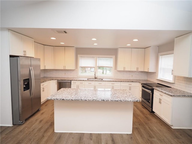 kitchen featuring appliances with stainless steel finishes, wood finished floors, a center island, and white cabinets