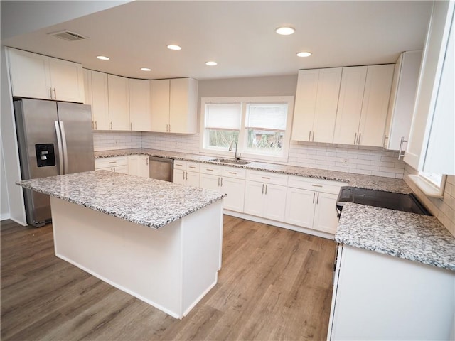 kitchen featuring light wood finished floors, appliances with stainless steel finishes, a sink, and white cabinetry