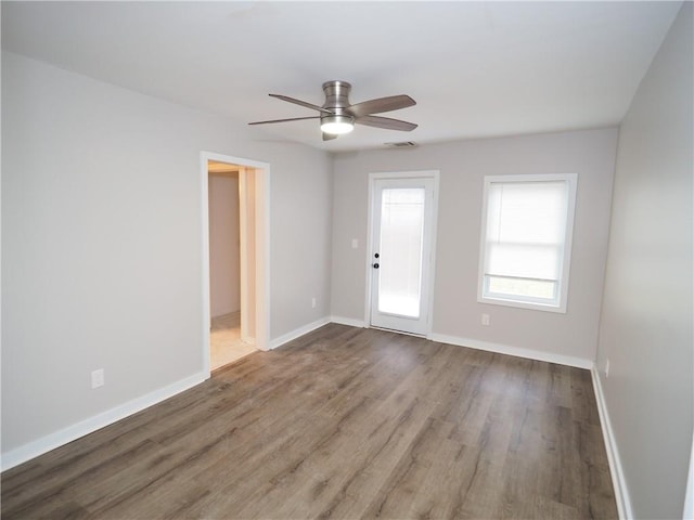 spare room with ceiling fan, wood finished floors, visible vents, and baseboards