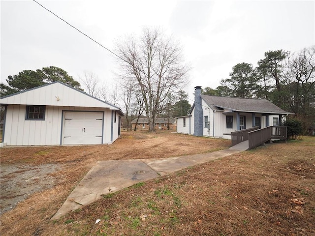 view of property exterior featuring a garage, a chimney, board and batten siding, and an outdoor structure