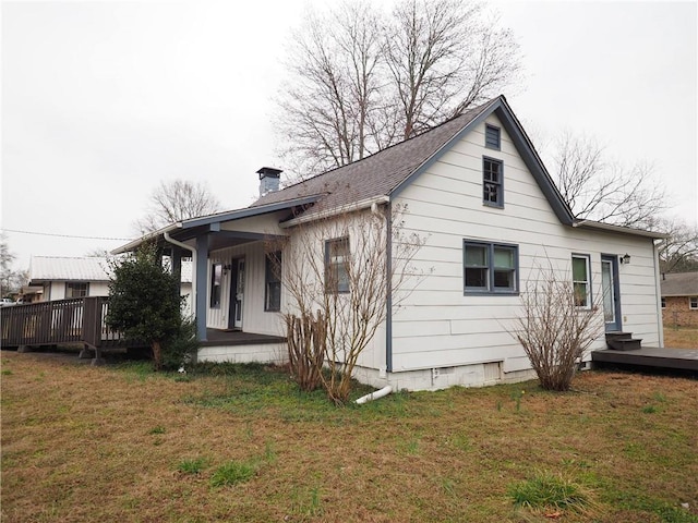 view of home's exterior featuring a yard, a porch, a chimney, and a shingled roof