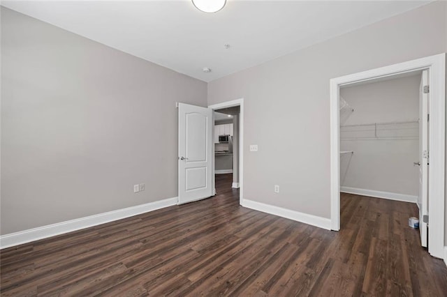 840 United Ave SE Unit 401, Atlanta, GA 30312 - unfurnished bedroom featuring dark wood-type flooring, baseboards, a spacious closet, and a closet