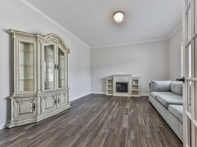 unfurnished living room featuring dark wood-type flooring, ornamental molding, a glass covered fireplace, and baseboards