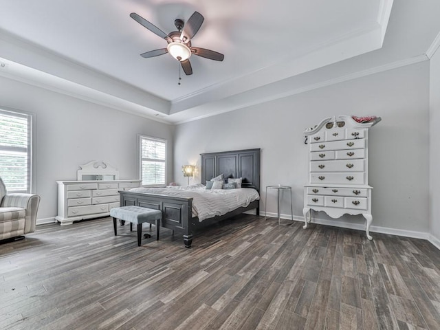 bedroom with a tray ceiling, dark wood finished floors, crown molding, baseboards, and ceiling fan