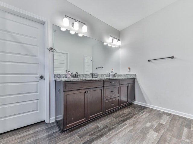 bathroom featuring wood finished floors, double vanity, and baseboards