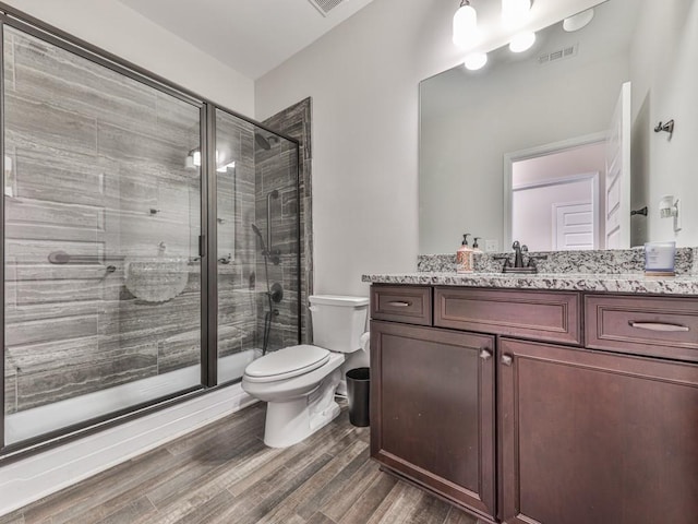 bathroom featuring vanity, wood finished floors, a stall shower, and toilet