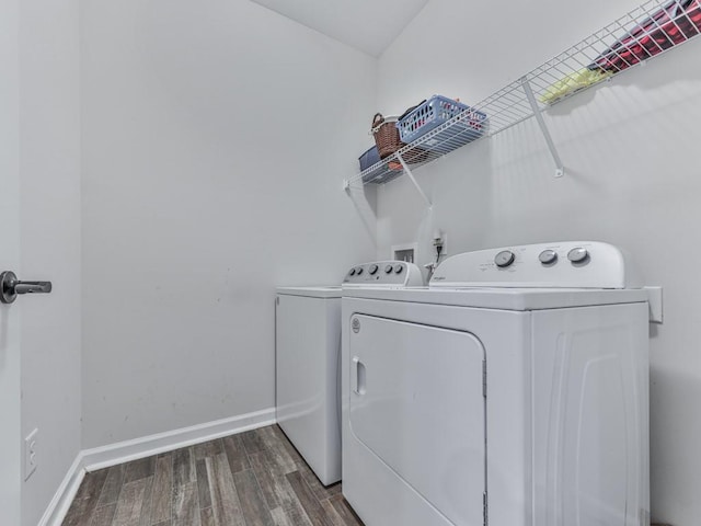washroom with washing machine and dryer, wood finished floors, and baseboards