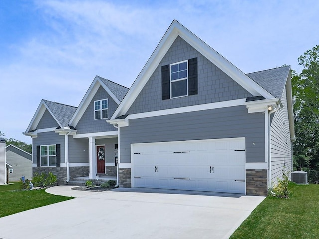 craftsman-style home featuring stone siding, concrete driveway, central AC, a front lawn, and a garage