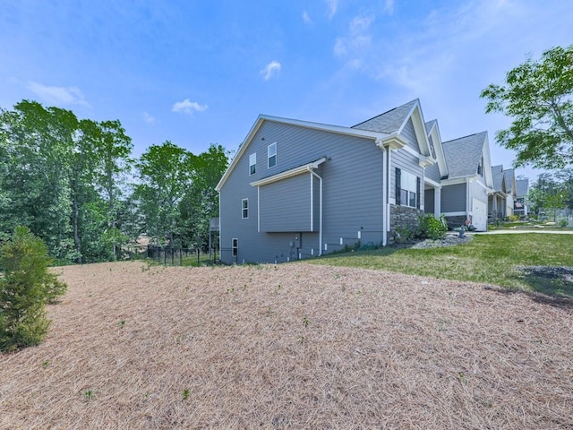view of side of home featuring stone siding and roof with shingles