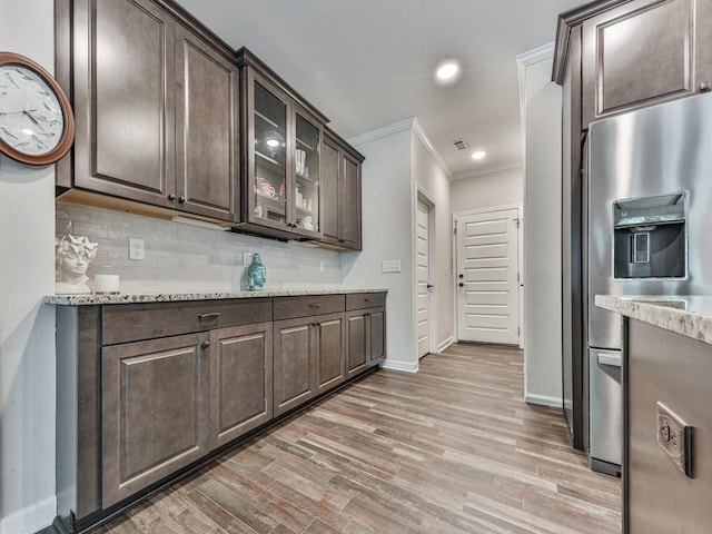 kitchen featuring stainless steel fridge with ice dispenser, dark brown cabinetry, ornamental molding, backsplash, and baseboards
