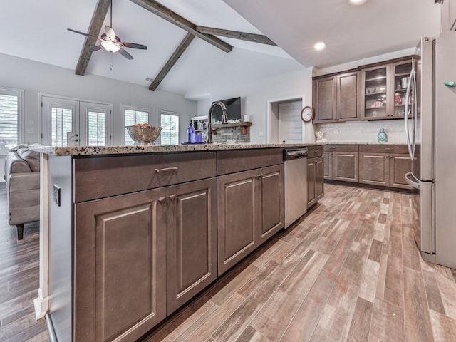 kitchen with stainless steel appliances, a ceiling fan, light wood-style flooring, backsplash, and open floor plan