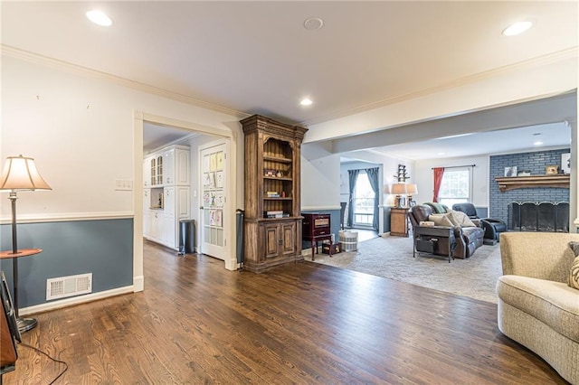 living room with a brick fireplace, crown molding, and dark hardwood / wood-style flooring